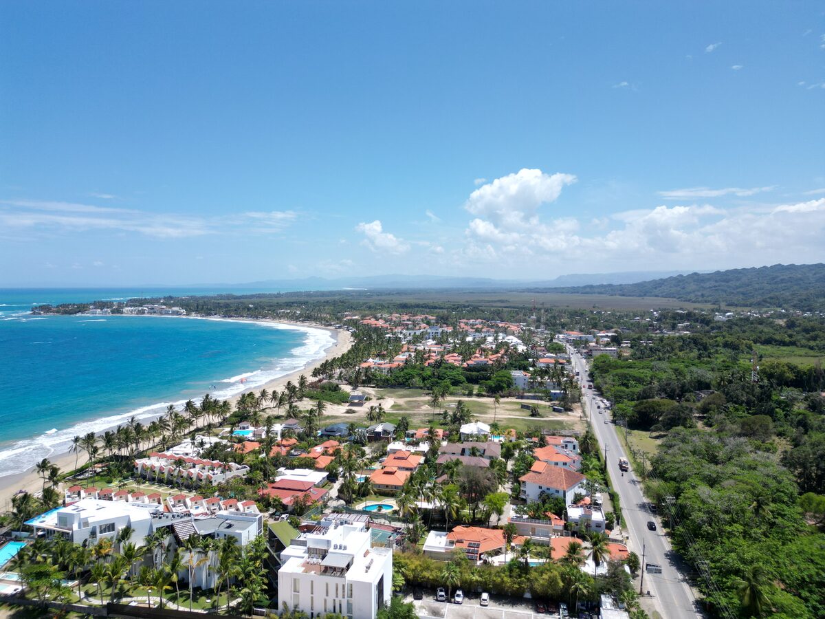 Aerial view of a coastal town with terra-cotta rooftops and palm-lined beach