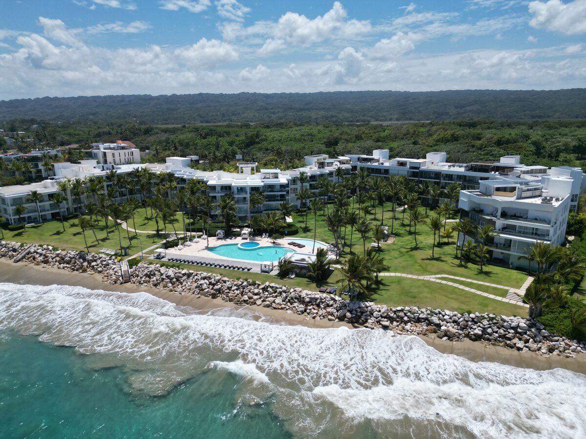 Aerial view of a beachfront resort complex with pool and palm trees