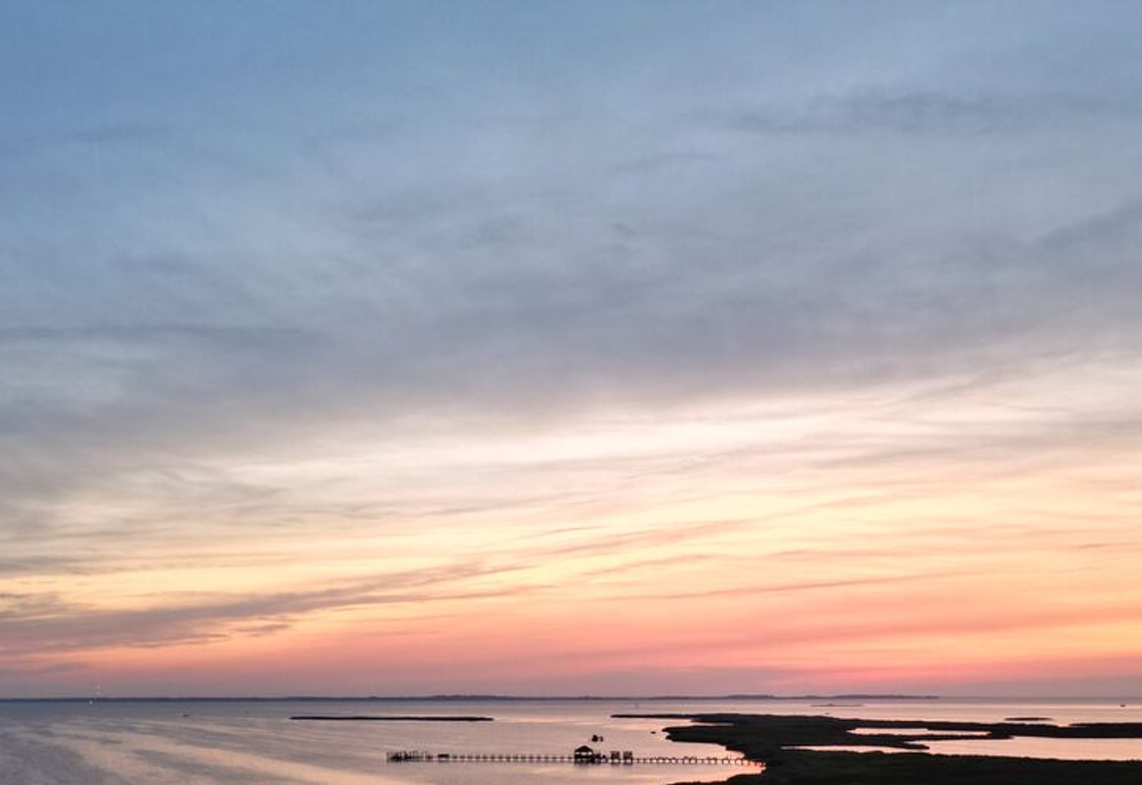 Aerial view of a sunset with warm horizon glow over marshland